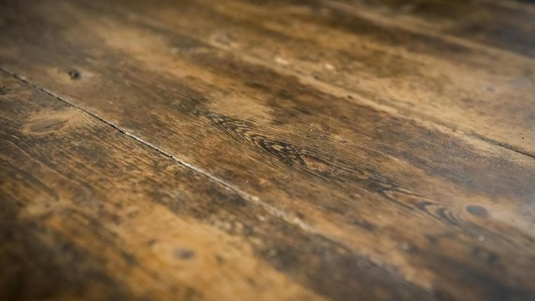 Ein schöner Holzboden mit warmen, natürlichen Farbtönen. Die Oberfläche zeigt eine rustikale, gealterte Struktur.