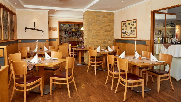 Een gezellig restaurant met houten tafels en stoelen. De sfeer is vriendelijk en uitnodigend, ideaal voor een ontspannen maaltijd.