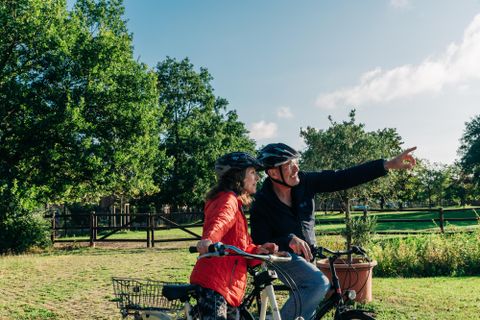 Een gelukkig paar fietst door een groen park. Ze dragen helmen en genieten van het uitzicht.