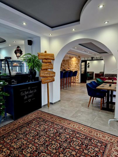 Een gezellig restaurant met moderne meubels en decoratieve elementen. De ruimtes zijn licht en uitnodigend, met een geplaveide vloer en een mooi tapijted.