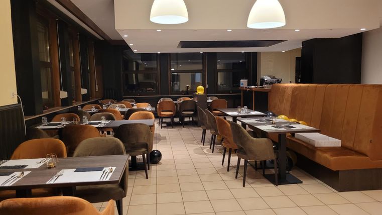 A modern restaurant with cozy chairs and tables. The lighting is friendly and creates an inviting atmosphere.