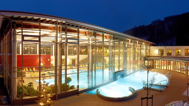 Ein modernes Schwimmbad mit großen Fenstern und stilvollem Design. Die Atmosphäre ist ruhig und einladend, ideal für Entspannung.