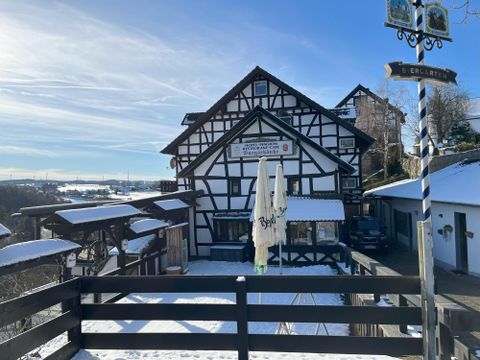 Ein traditionelles Fachwerkhaus im Winter mit Schnee bedeckt. Der Himmel ist klar und blau, und es gibt eine schöne Aussicht auf die Landschaft.