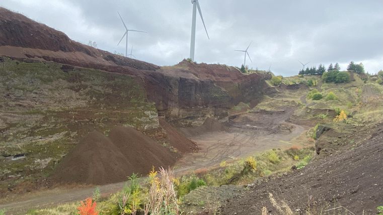Hier hat man einen Ausblick auf den Vulkan. Man sicht leicht bewachsene Hügel. Der Himmel ist bewölkt.