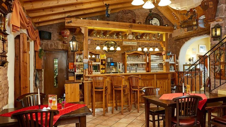 Ein einladendes Restaurant mit einer Holztheke und gemütlichen Tischen. Die rustikalen Möbel schaffen eine warme Atmosphäre.