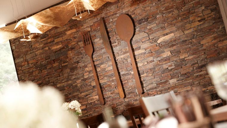 A stylish stone wall with large, decorative utensils (fork and spoon). The room has an inviting atmosphere for guests.