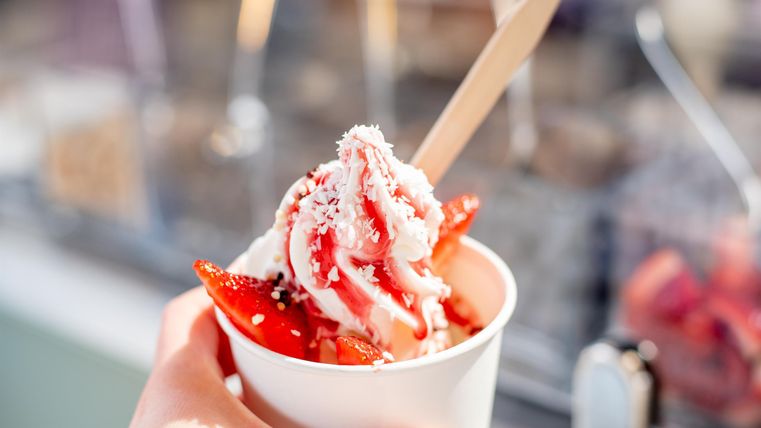 Een beker met romige ijs en verse aardbeien. Daarop ligt een fijne laag kokosrasp.