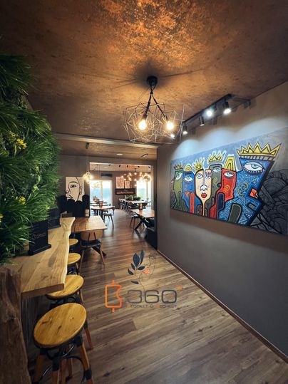 Een modern vormgegeven ruimte met houten vloeren en woonkamermeubilair. Aan de wand hangt een kleurrijk kunstwerk met gestileerde gezichten.