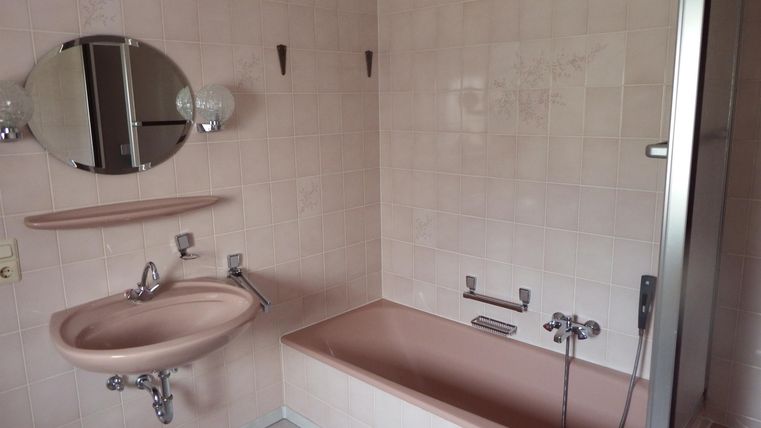 A bathroom with a bathtub, a sink, and a shower. The walls are brightly tiled and the light is diffuse.
