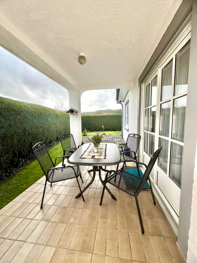 A cozy outdoor area with a table and chairs. Surrounded by green hedges and a tranquil atmosphere.