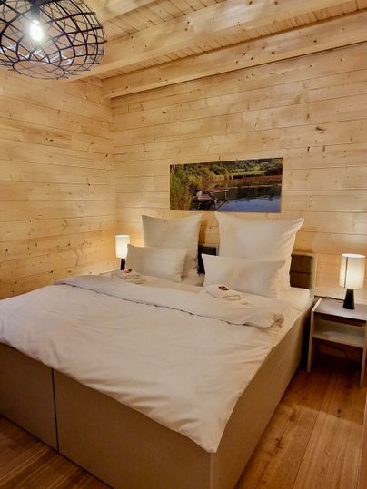 Ein gemütliches Schlafzimmer mit Holzverkleidung und einem großen Bett. Neben dem Bett stehen zwei Nachttische mit Lampen.