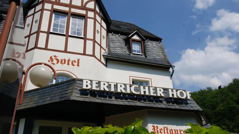 Een charmant hotel met traditionele architectuur en een uitnodigend bord. Het bevindt zich in een groene omgeving.