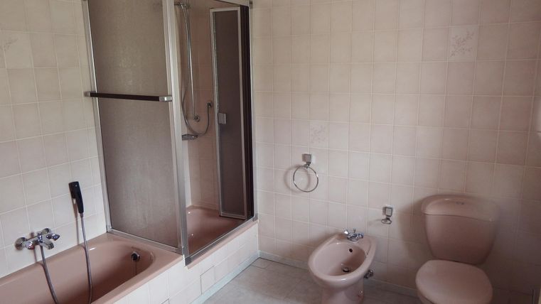 A simple bathroom with a shower, a bathtub, and a bidet. The walls are brightly tiled, and the space feels clean and tidy.