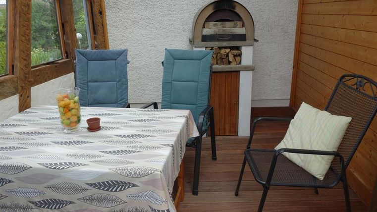 Een gezellige ruimte met een tafel en stoelen. Een houtkachel en een fruitschaal geven de ambiance een uitnodigende sfeer.