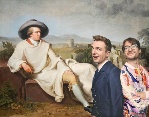 Twee jonge mannen voor een schilderij waar een man op een steen zit. Op de achtergrond is een ronde toren van een kasteel.