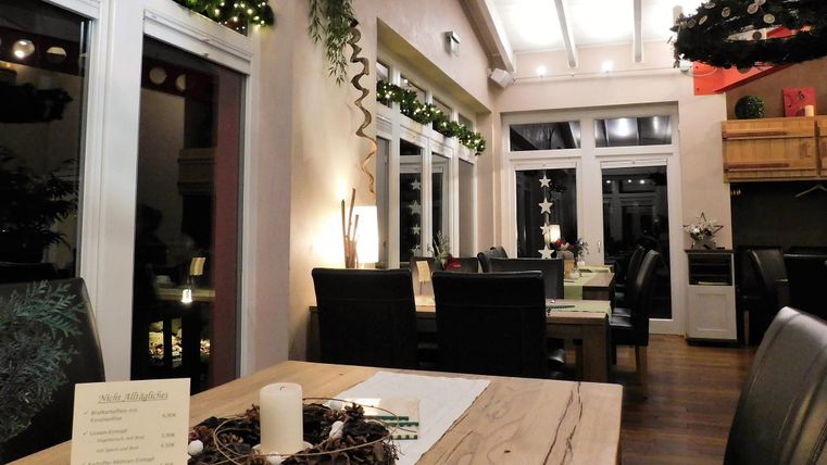 Een gezellig restaurant met feestelijke decoratie. De tafels zijn mooi gedekt en het licht zorgt voor een uitnodigende sfeer.