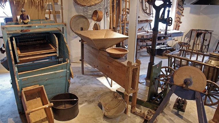 Interior view of a museum with historical agricultural implements and tools made of wood and metal.