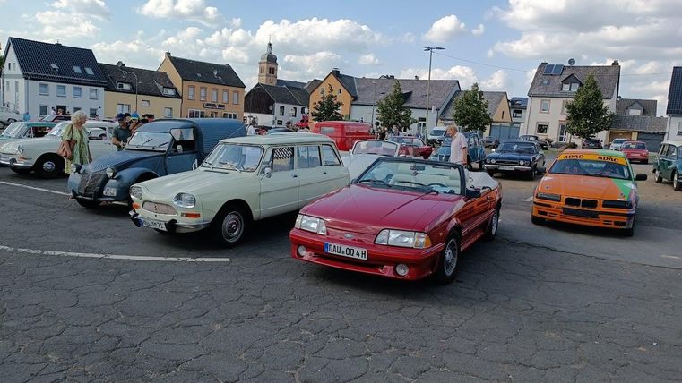 Een rode oldtimer omringd door andere oldtimers