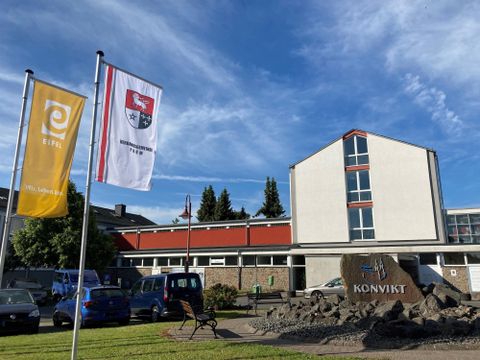 Ein modernes Gebäude mit Fahnen im Vordergrund. Der Schriftzug "KONVIKT" ist gut sichtbar.