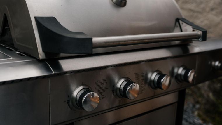 Ein Grill aus Edelstahl steht auf der Terasse bereit.