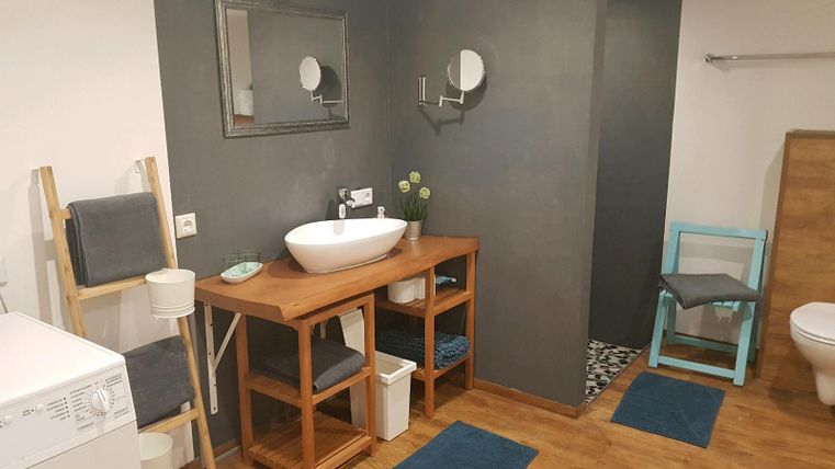 Een moderne badkamer met houten planken en een grote wastafel. De vloer is van hout, en er is een moderne toiletruimte.