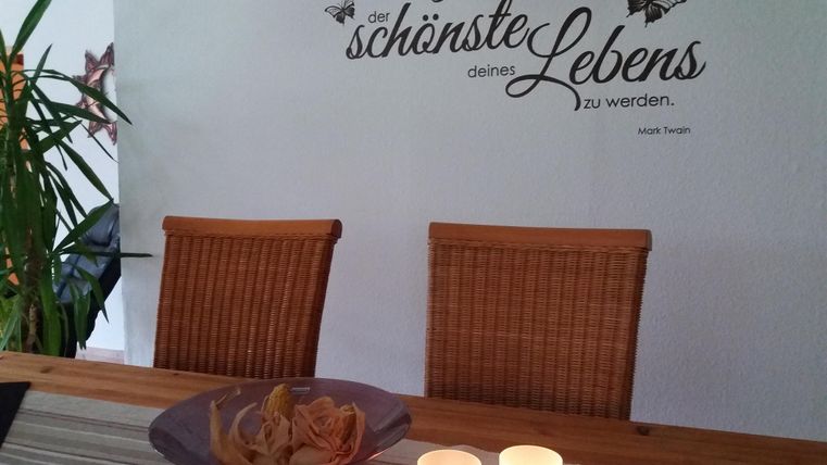 An inviting dining table with two chairs and a decorative bowl. There is an inspiring quote on the wall.