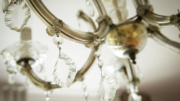 Ein eleganter Kronleuchter mit transparenten Kristallanhängern. Das Licht reflektiert sanft durch die dekorativen Elemente.