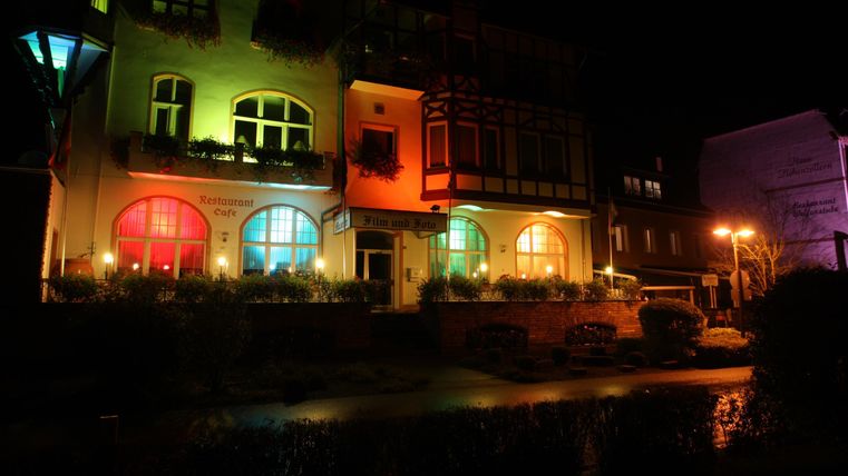 Eine bunte Straße mit beleuchteten Gebäuden in der Nacht. Die Fenster erstrahlen in verschiedenen Farben und schaffen eine einladende Atmosphäre.