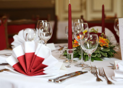 An elegantly set table with red and white cutlery.
Decorative napkins and flower arrangements create a festive atmosphere.