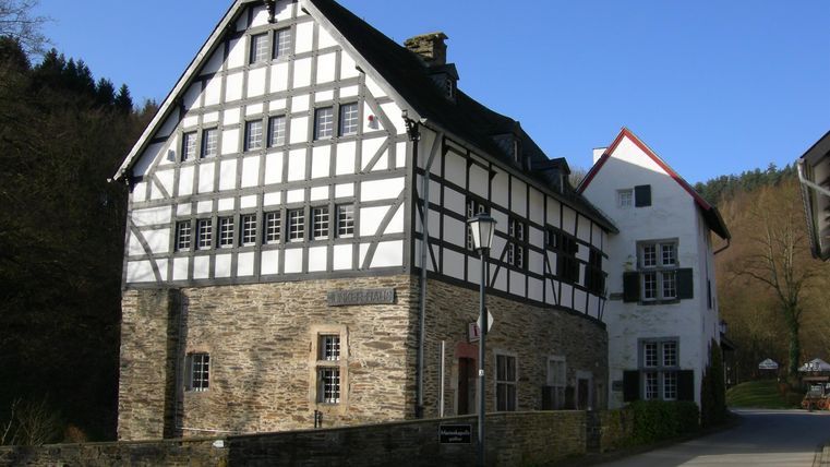 Ein historisches Fachwerkhaus mit einer Steinbasis und einem klaren Himmel. Die Architektur zeigt traditionelle Elemente und harmoniert mit der Umgebung.