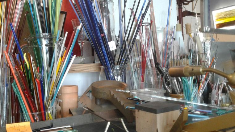 Werkplek met verschillend gekleurde glazen buisjes en gereedschap