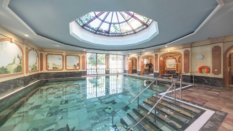 Een elegant zwembad met een kunstzinnig daklicht en stijlvolle wanden. Het wateroppervlak weerspiegelt de omgeving en zorgt voor een ontspannende sfeer.