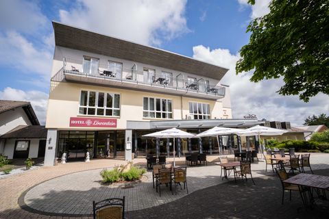 Een modern hotel met een uitnodigende buitenruimte. Er zijn tafels en parasols om gasten een comfortabele plek te bieden om te ontspannen.