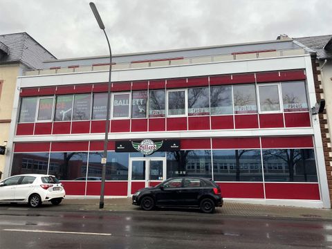 Een modern gebouw met een rode en witte façade. De ramen zijn groot en reflecteren de omgeving.