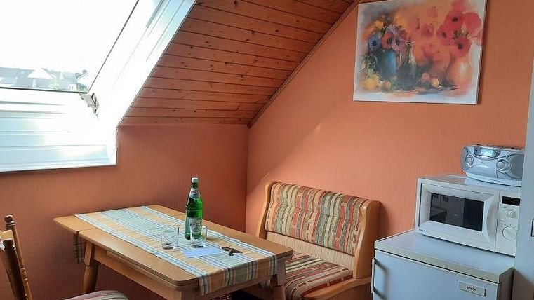 A cozy dining area with a table and two chairs. Next to the table are a water bottle and a refrigerator.