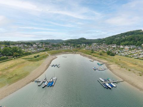 Ein ruhiger See mit Bootsanlegestellen und sanften Hügeln im Hintergrund. Die Landschaft ist grün und die Atmosphäre ist friedlich.