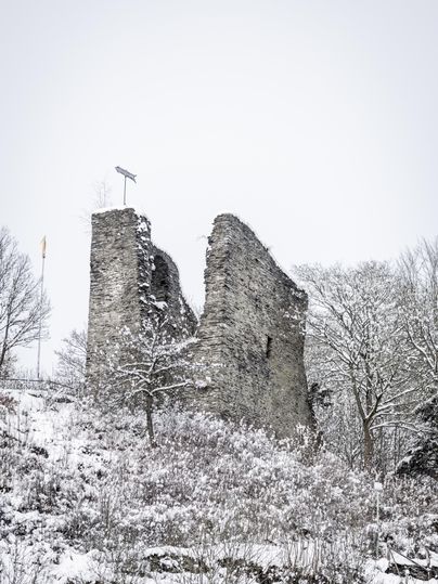 Eine alte Ruine inmitten von Schnee. Umgeben von Bäumen, die ebenfalls mit Schnee bedeckt sind.