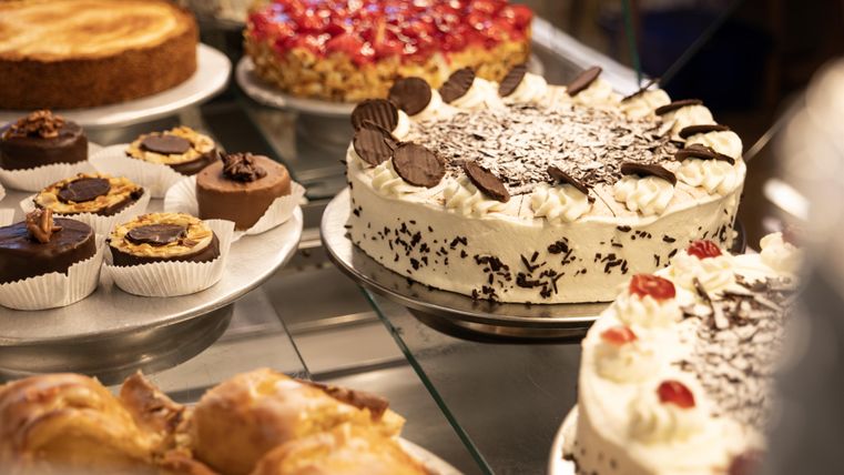 A selection of cakes and sweet treats, including tarts, muffins, and pastries. The display is appetizing and diverse.