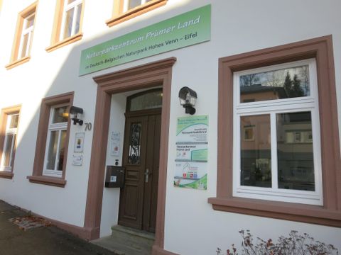De afbeelding toont het gebouw van het Natuurcentrum Human Land met een uitnodigende voordeur. Boven de deur hangt een bord met de naam van de instelling.