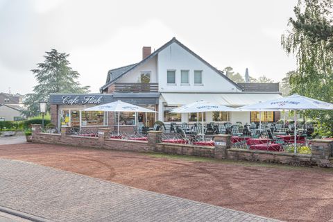 A cozy café with an outdoor area and sun umbrellas. The surroundings are quiet and inviting.
