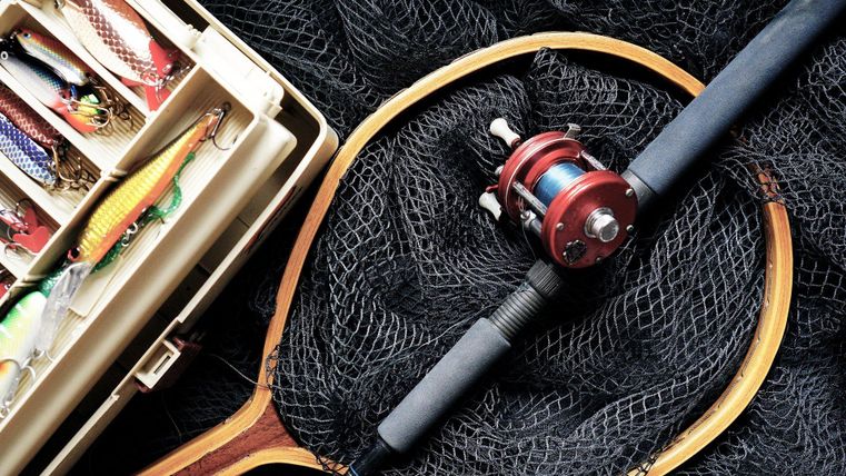 Angelzubehör mit Köderbox, Angelrute und Netz.