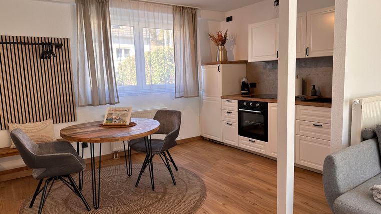 A cozy living space with a round table and four chairs. The bright, modern kitchen is well-equipped and offers plenty of natural light.