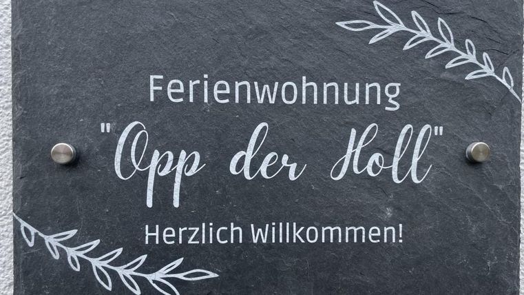 Een bord voor een vakantiehuis genaamd "Opp der Holl". Het zegt: "Hartelijk Welkom!"