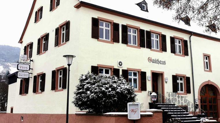 Ein hübsches Gasthaus mit einer schlichten Fassade und traditionellen Fenstern. Es ist von Schnee umgeben und vermittelt eine gemütliche Atmosphäre.