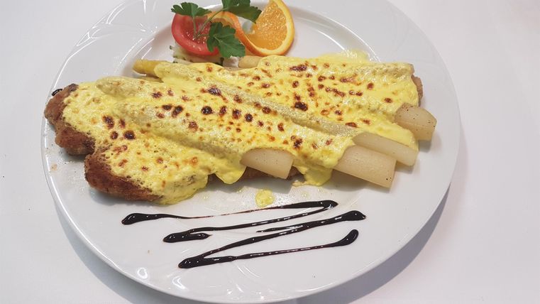 Ein Teller mit überbackenen Crepes, gefüllt mit köstlichem Gemüse. Dazu garnierte Früchte und eine süße Sauce.