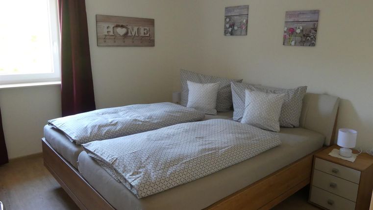 Ein gemütliches Schlafzimmer mit einem Doppelbett und zwei Kissen. An den Wänden hängen Bilder und es gibt einen Nachttisch neben dem Bett.