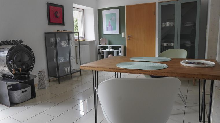 Ein modernes Esszimmer mit einem Holztisch und eleganten Stühlen. Die Wände sind in sanften Farben gehalten, und es gibt dekorative Kunstwerke.