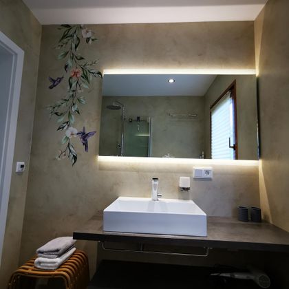 Een moderne badkamer met een elegante wastafel en een grote spiegel. De muren zijn versierd met een zachte decoratie van florale motieven.