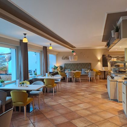 A modern café with bright walls and cozy tables. The decor is inviting and colorful.