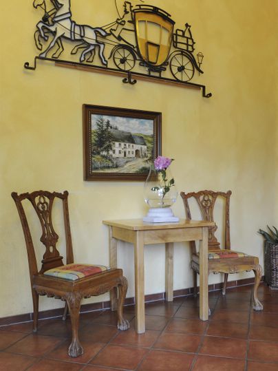 Ein gemütlicher Eingangsbereich mit zwei Stühlen und einem kleinen Tisch. An der Wand hängt eine dekorative Grafik und ein Bild.